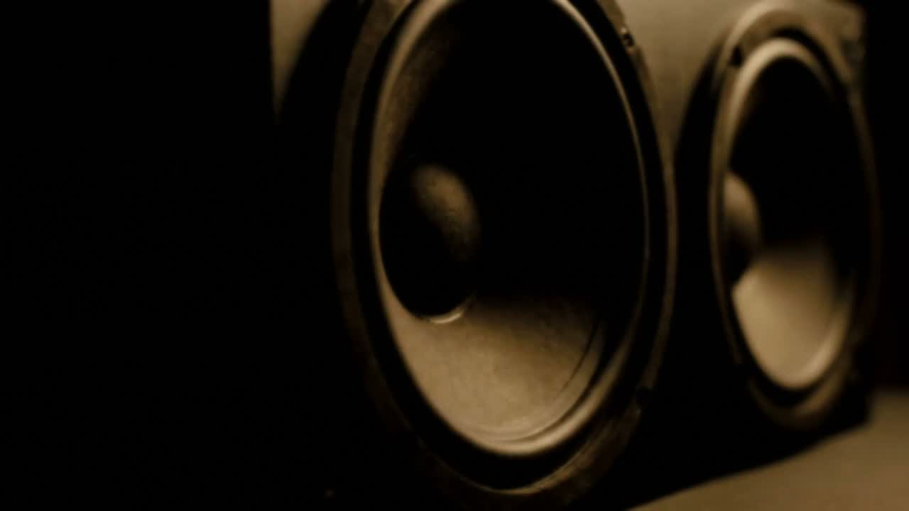 Two speaker drivers in the dark, lit along one edge